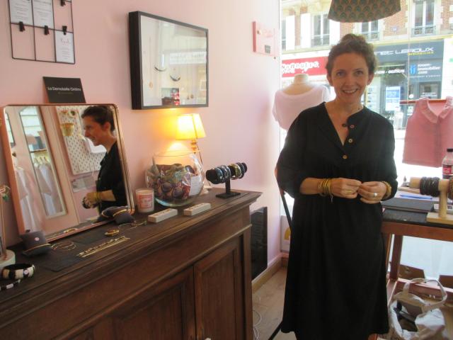 Mademoiselle Gridou pose dans la boutique devant un meuble où se trouvent exposés les bijoux