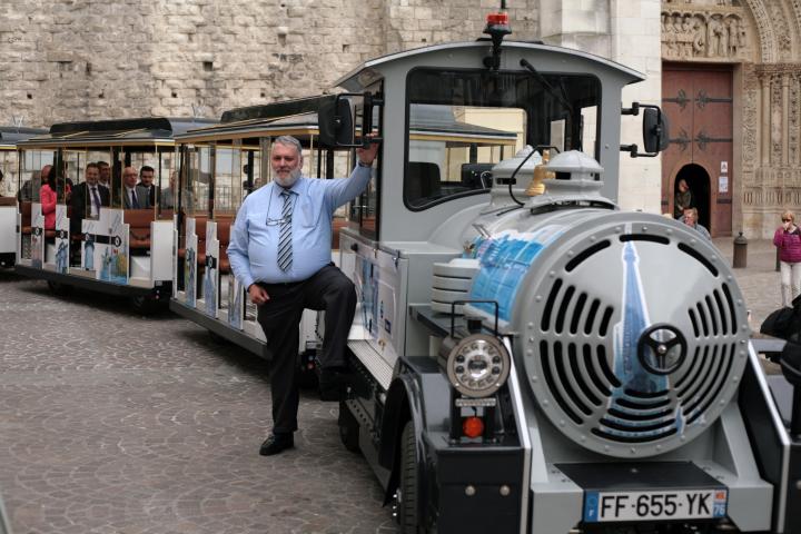 Le train gris clair, avec sa locomotive et ses trois wagons devant la cathédrale de Rouen