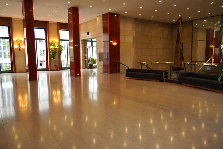 Foyer du premier étage de la Halle aux Toiles avec colonnes rouges, sols clairs.