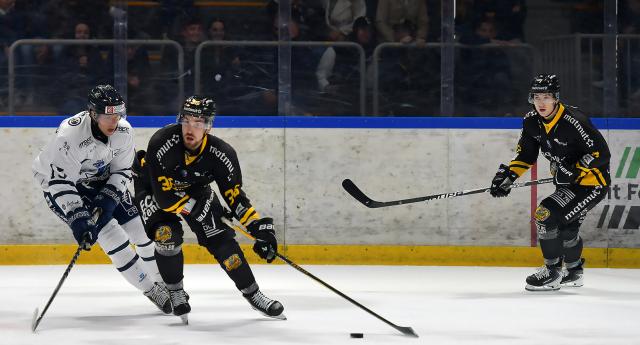 un joueur de Rouen en maillot noir passe devant un joueur de Gap en maillont blanc avec le palet au bout de la crosse 