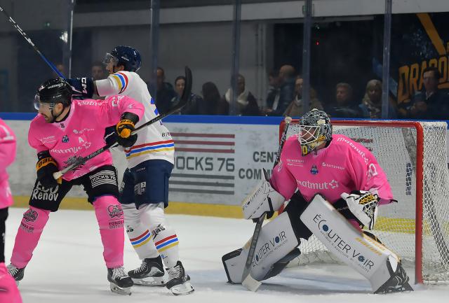 Un défenseur rouennais en maillot rose (pour Octobre rose) empêche un attaquant de Nice en maillot blanc de récupérer le palet devant la cage de hockey de Rouen
