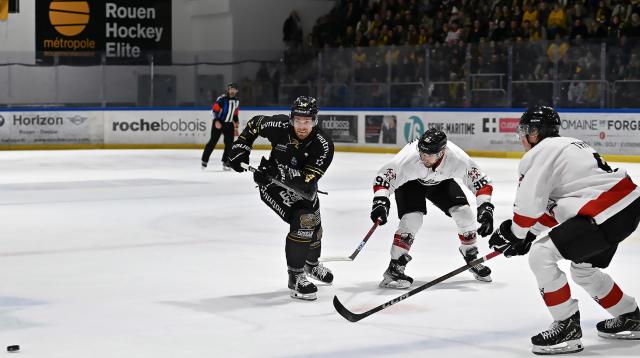 le joueur de Rouen en maillot noir s'élance sur la glace devant deux joueurs de Chamonix en maillont blanc pour récupérer le palet