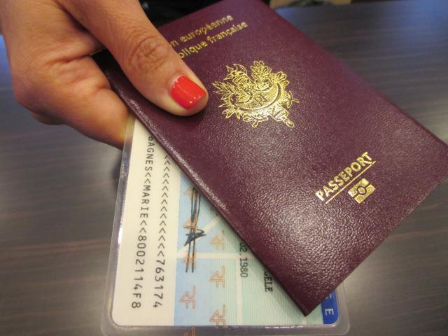 Une main tient une carte d'identité et un passeport  