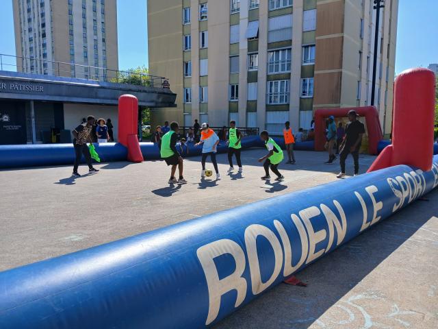 des jeunes en chasuble jaune jouent au football sur un terrain monté par la Ville de Rouen sur la dalle de la Grand-Mare