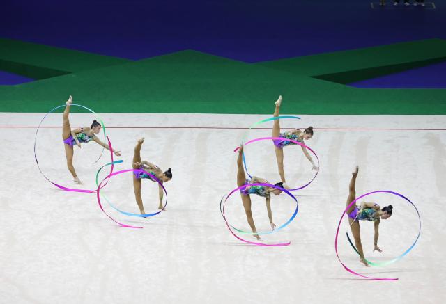 Cinq gymnastes dans une compétition de ruban par équipe