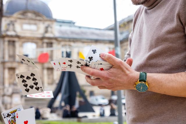 un magicien fait voler des cartes à jouer devant un monument