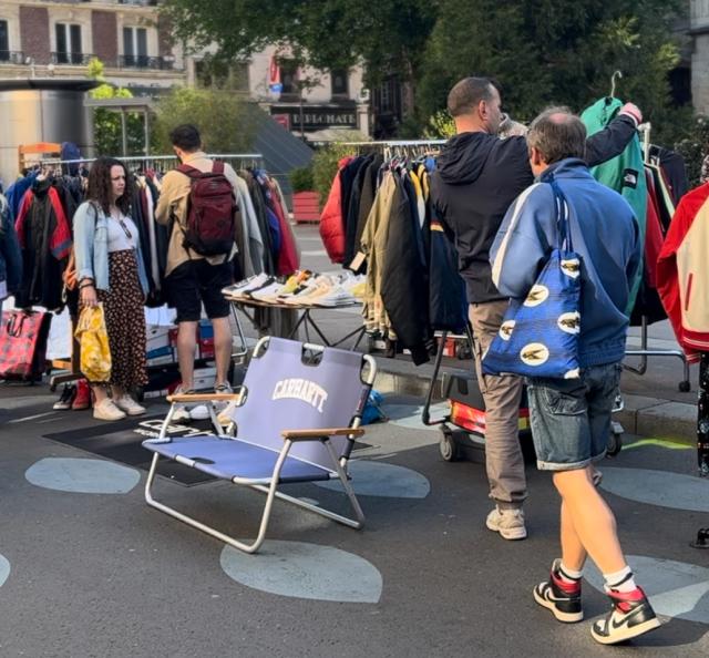 Des gens regardent des étals disposés dans la rue Jeanne d'Arc piétonne dans le cadre des Puces