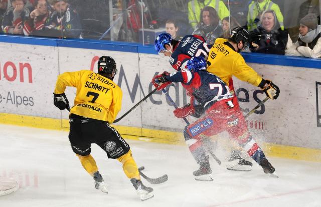 deux Rouennais en maillot jauen sur la gace de Grenoble entourent un joueur grenoblois en maillot bleu pour lui prendre le palet 